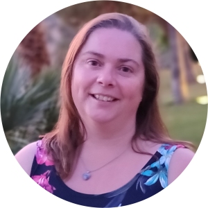 Photo of Emma Ashworth. Emma is a white woman with shoulder length brown hair. She's wearing a floral top and there's a garden behind her in the photo.