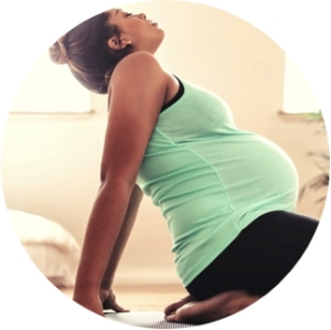 Photo of woman in yoga pose. The woman is brown, and is wearing a mint green top and black trousers. She has dark hair tied back into a bun.